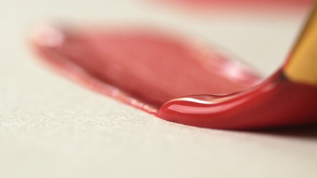 An artist paints with red acrylic paint on paper. A close-up of a brush drawing a line. Hobby and leisure concept