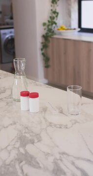 Vertical video: Camera is shifting focus while jars are sitting on marble top, revealing carafe