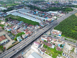 Fototapeta premium Aerial view of an urban highway interchange connecting residential and industrial districts with active traffic