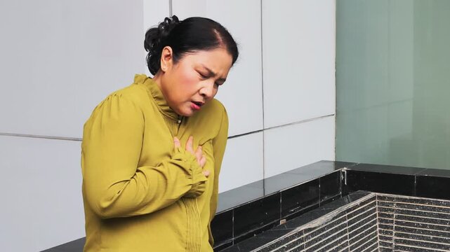 old Asian senior woman suffering from GERD or acid reflux