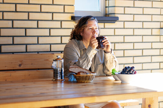 Senior Woman in outdoors gazebo slowly eats breakfast alone