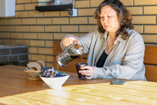 Senior Woman in outdoors gazebo slowly eats breakfast alone