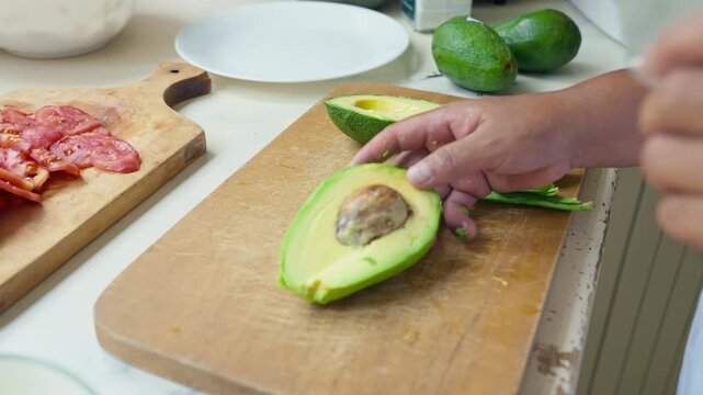 Peeling a fresh ripe avocado with a kitchen knife, close up