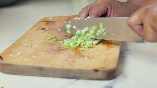 Dicing fresh celery on a wooden board.