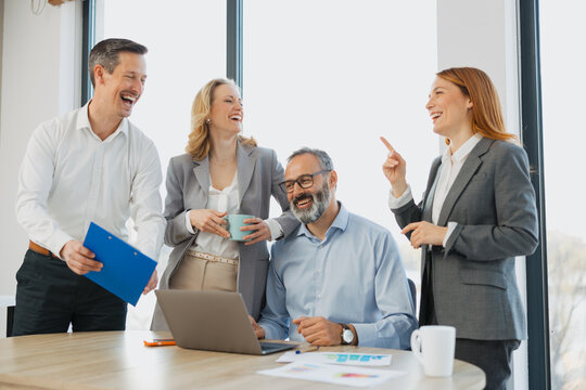 Group of four diverse business people working together around a table in a modern office.