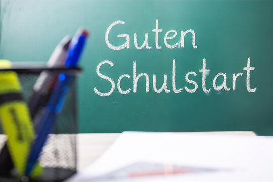 Tafel mit hinzugef&uuml;gtem Text GUTEN SCHULSTART hinter einem Schreibtisch