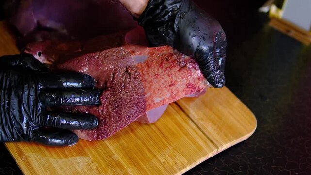 to peel the beef liver. woman hands delicately peel away the packaging from beef liver, signifying the beginning of a culinary journey. The texture and freshness evoke anticipation for delicious
