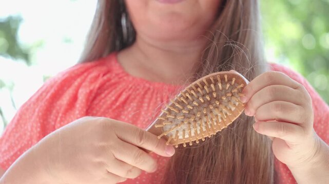 woman combing long brown hair, tangles fallen hair wound on brush pins, hair loss, health, treatment alopecia, hormonal imbalance