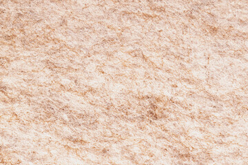 Horizontal macro top view shot of a dense beige and light brown wool felt texture fabric surface with a chaotic organic fiber structure pattern detail © moryachka