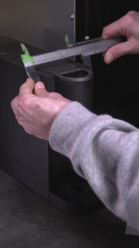 An engineer takes measurements of a coffee machine to later glue a 3D-printed dog body to it.