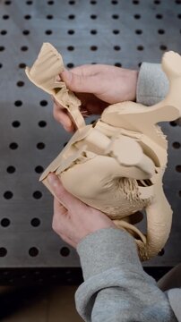 An engineer removes support from a 3D-printed dog body before gluing it to a coffee machine.