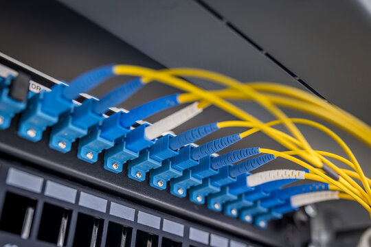 Blue LC duplex fiber optic connectors and yellow single-mode cables in server rack panel
