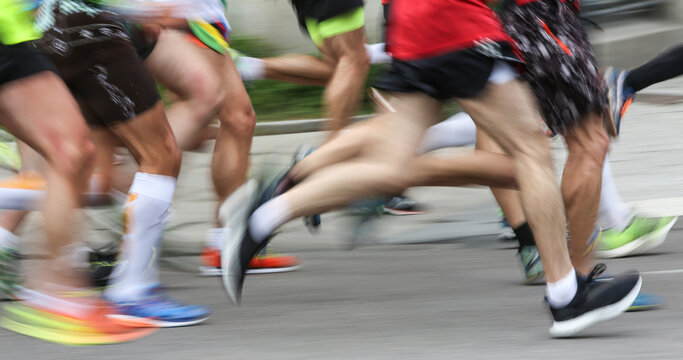 Blurred marathon runners in wide sports banner with fast legs and colorful shoes. Panoramic road race image with motion blur for website header or advertising