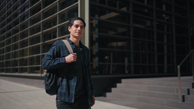 Young latin man student with backpack walking in modern city. Freelancer inspiration