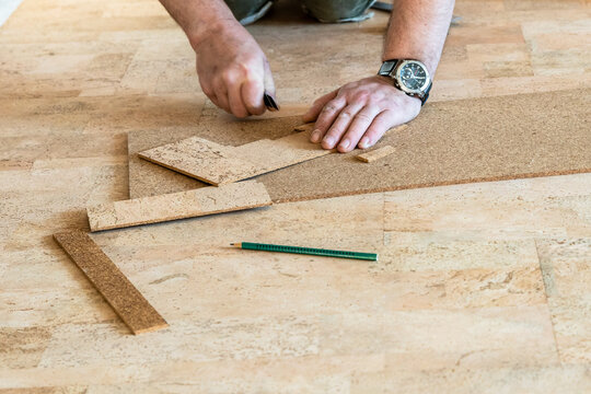 repairman cuts cork tile during flooring laying