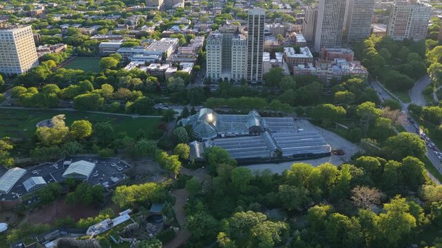 Golden hour light illuminating Lincoln Park Zoo and its conservatory with surrounding Lincoln Park neighborhood skyscrapers and buildings in Chicago, Illinois from above