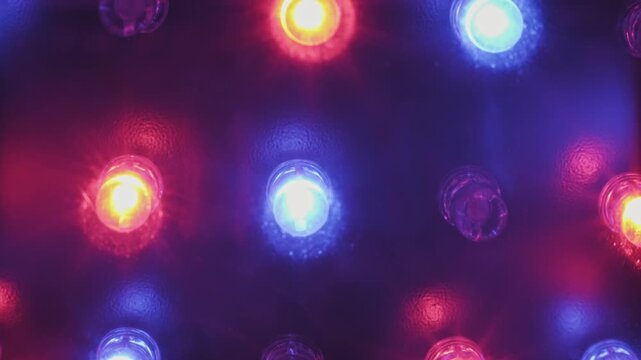 Bright red green and blue LED lights blink sequentially on a dark panel in a close-up shot. Concept of digital technology, nightlife entertainment, and abstract electronic displays.