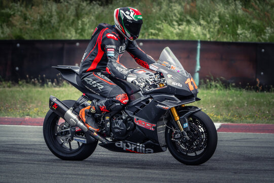 Regular training in Riga, Latvia, Bikernieki on 12-05-2026  Motorcyclist leaning on a racing motorcycle in a grassy area