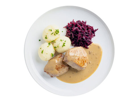 A plate of food featuring two pieces of meat in gravy, three potato dumplings topped with herbs, and a serving of red cabbage.