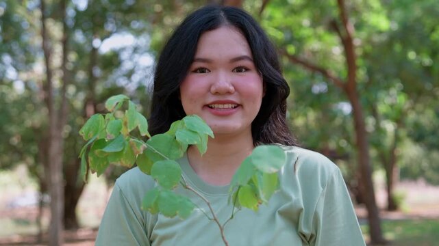 Embracing Green: A portrait of a woman joyfully holding a vibrant green plant in a lush natural setting. The image evokes a sense of peace, love, care, and the interconnectedness of all living things.