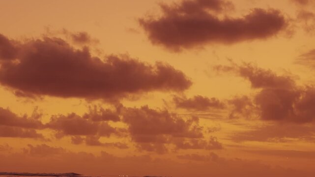 An atmospheric wide shot of the sky during twilight. The clouds are tinted with amber and bronze hues, creating a moody and dramatic backdrop for video production.