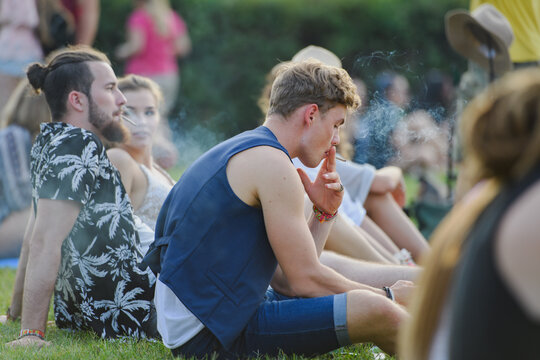 Festival goers taking break and smoking during outdoor summer festival or party.