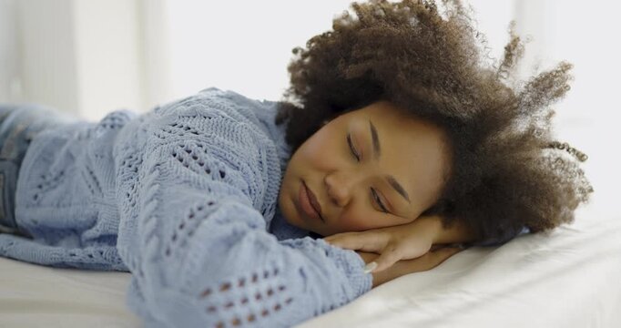 Portrait of beautiful African American woman relax face in winter bedroom. Closeup beauty fashion girl healthy makeup facial treatment perfect glow skin. Smile happy hygge black girl in blue sweater