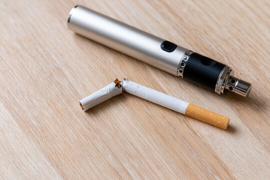 The Modern Electronic Cigarette and Broken Cigarette on Wooden Surface Still Life