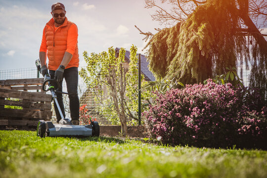 Aeration of the lawn in the garden. Aerator on green grass. Gardener Operating Soil Aeration Machine on Grass Lawn. Lawn scarification.