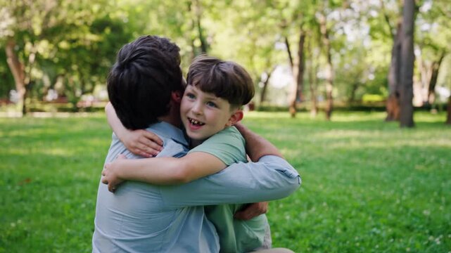 Happy and loving father laughs warmly as catches smiling son