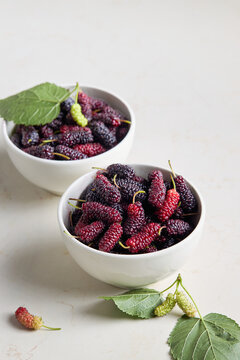 Organic mulberries with green leaves on a light background