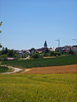 germany, vibrant colorful summer fields stretching toward ostfildern kemnat with charming residential skyline beneath crystal clear blue sky