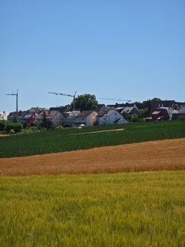 germany, expansive countryside panorama featuring colorful summer fields and ostfildern kemnat skyline with construction cranes under blue sky