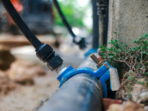Close-up of water pipeline connection with HDPE fitting installed outdoors, representing water supply infrastructure, utility maintenance, plumbing system, engineering, distribution, public services.