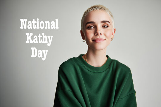 A young woman with short blonde hair and a green sweatshirt smiles against a neutral background. National Kathy day concept