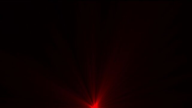 Intense red light flare originating from the bottom center with soft rays of light extending upwards against a solid black background surface