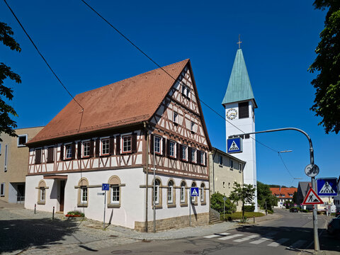germany, charming historic timbered old townhall beside village church steeple in ostfildern kemnat beneath brilliant summer blue sky