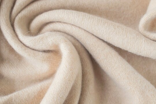 Cashmere beige fabric, top view. Draped, texture, background. Natural wool clothing.