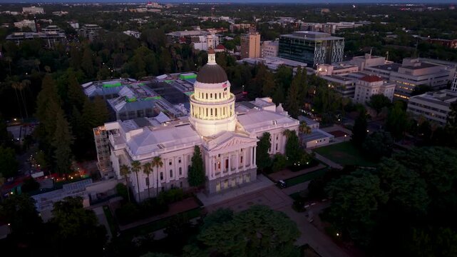 Views show the west side of the California State Capitol in Sacramento at night with lights on and the annex being built in the east