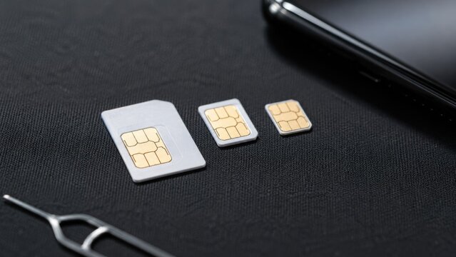 Collection of Standard Micro and Nano SIM Cards with Smartphone and Eject Tool on Black Background