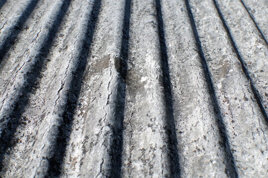The texture of the gray corrugated roof surface appears aged, dusty, and weathered by time, featuring a pattern of diagonal lines. This texture is suitable as a background for industrial, construction