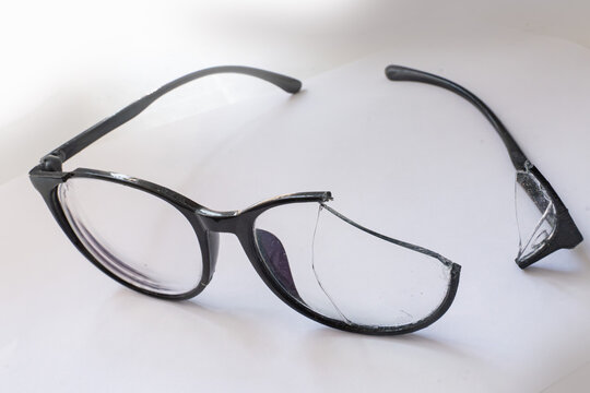 Closeup of Broken Eyeglasses with Cracked Lens on White Surface