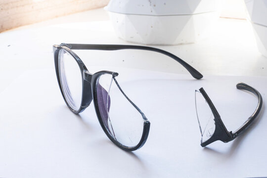Closeup of Broken Eyeglasses with Cracked Lens on White Surface
