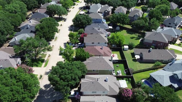 Single family properties border expansive green zones near Leonard and Helen Johns Community Park in Flower Mound, TX. Dark roof shingles integrate with heavy canopy cover, suburbs neighborhood