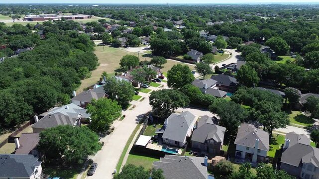 Local housing developments sit tucked against vast forest corridors. Neutral-toned rooftops contrast with vibrant foliage, highlighting suburban integration with nature in Flower Mound, Texas