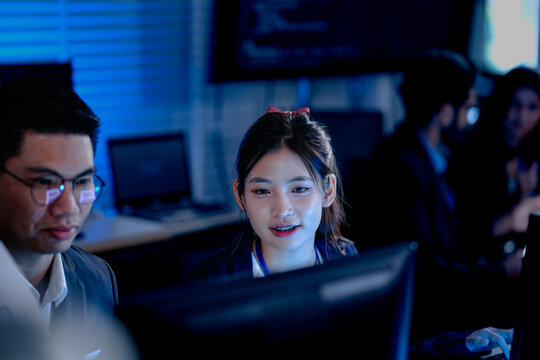 Monitoring AI training progress. Specialists oversee a machine learning model's training observing real time metrics on screen discussing adjustments via tablet interface late night.