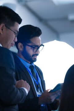 Monitoring AI training progress. Specialists oversee a machine learning model's training observing real time metrics on screen discussing adjustments via tablet interface late night.