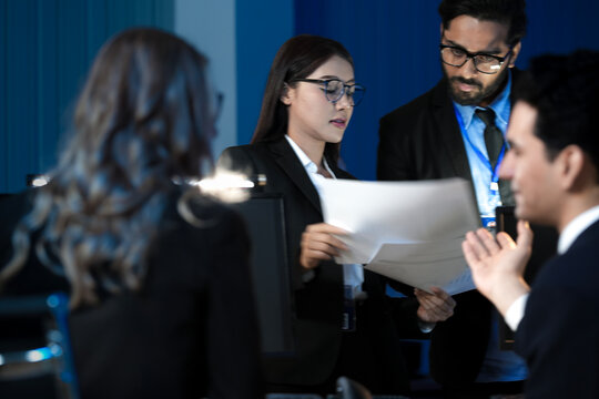 Data integrity check night shift Diverse team meticulously audits financial performance comparing figures tablet screen printed reports ensuring accuracy crucial validation process underway hub.