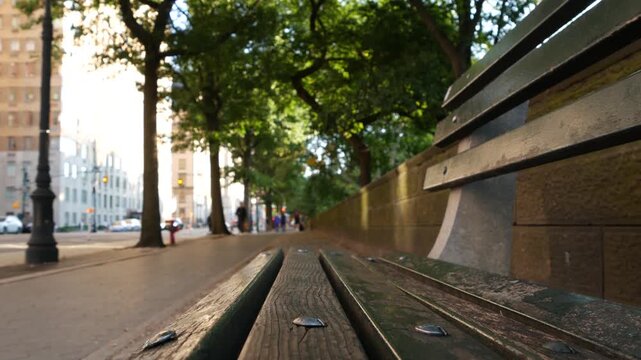 Wooden bench near Central Park in New York City, United States. Cars and people on street in Manhattan, USA. Defocused perspective.