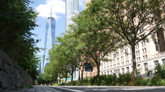 Lower Manhattan Downtown Financial District, New York City, United States. One World Trade Center skyscraper building, Freedom tower from Battery park. Summer trees greenery, West street perspective.